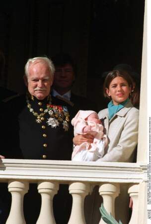 1999 : Charlotte Casiraghi est aux côtés du Prince Rainier et tient sa sœur Alexandra de Hanovre dans ses bras lors de son apparition au balcon. 