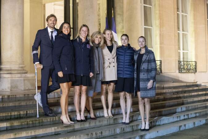 A l'occasion de sa rencontre avec l'équipe de France féminine de tennis, Brigitte Macron un trench gris assorti à son écharpe. 