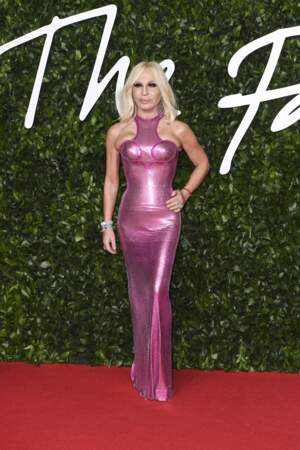 Donatella Versace glamour telle une pin'up dans une robe moulante rose flashy de la maison Dior.