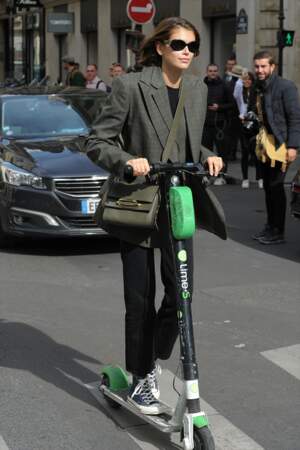 A la Fashion Week de Paris, Kaia Gerber adopte la trottinette dans les rues de la capitale, jamais sans son The Story Bag de Alexander McQueen.