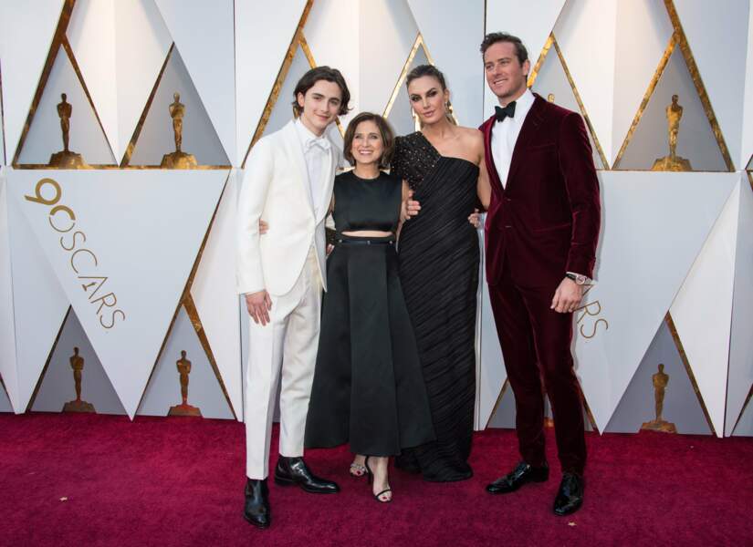 En mars 2018, Timothée Chalamet en costume blanc, pose avec sa maman, Nicole Flender, Elizabeth Chambers et son mari Armie Hammer lors de la 90ème cérémonie des Oscars .