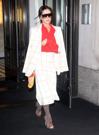 Victoria Beckham apporte une note pop et coloré à son ensemble blanc en l'associant à un chemisier vaporeux rouge et des stilettos façon léopard.