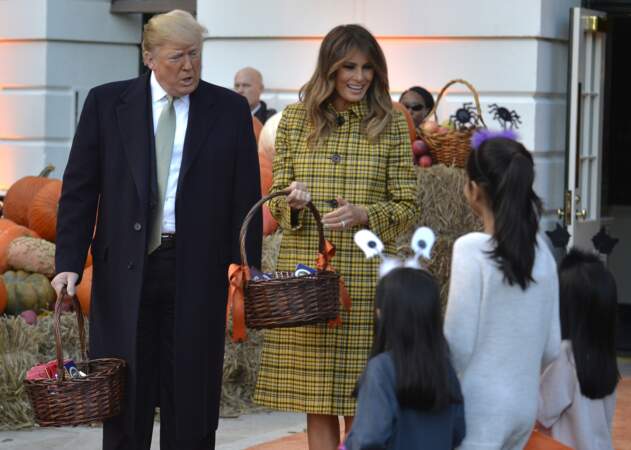 Melania Trump ose un manteau écossais jaune signé Bottega Veneta pour la distribution de sucreries à la Maison Blanche à l’occasion d’Halloween, le 28 octobre 2018.