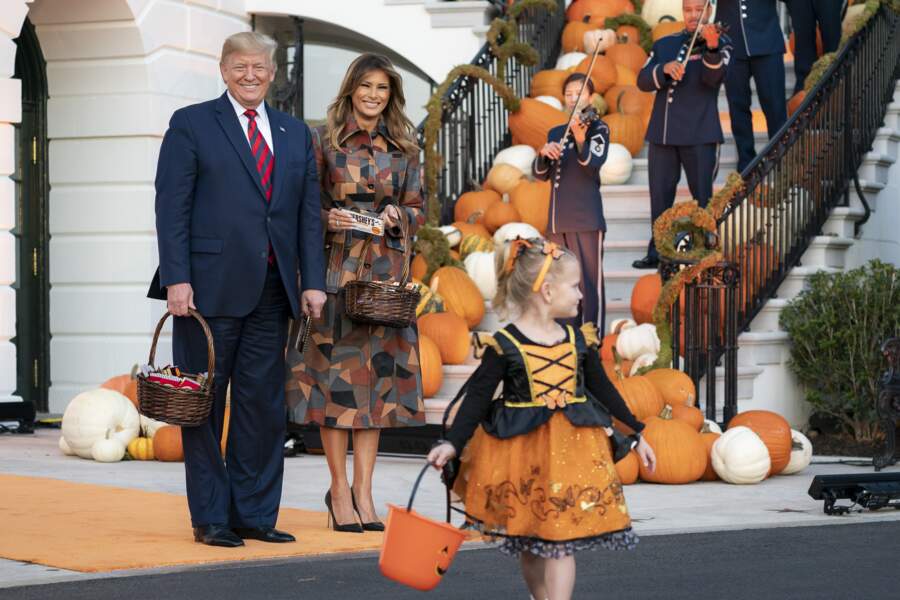 Melania Trump audacieuse dans un long trench-coat patchwork aux nuances automnales de la dernière collection Michael Kors pour célébrer Halloween à la Maison Blanche, le 31 octobre 2019. 