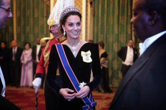 Malgré la tiare et le collier très "royals", Kate Middleton twiste avec une robe en velours au décolleté hollywoodien signé Alexander McQueen à Buckingham Palace, le 11 décembre 2019.