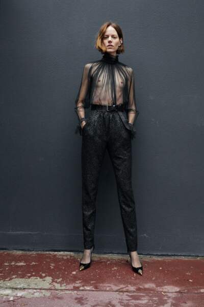 Liya Kebede sensuelle dans une blouse en organza noire transparente portée avec un pantalon à pinces pailleté pour la dernière campagne "Le Smoking" signée Saint Laurent.