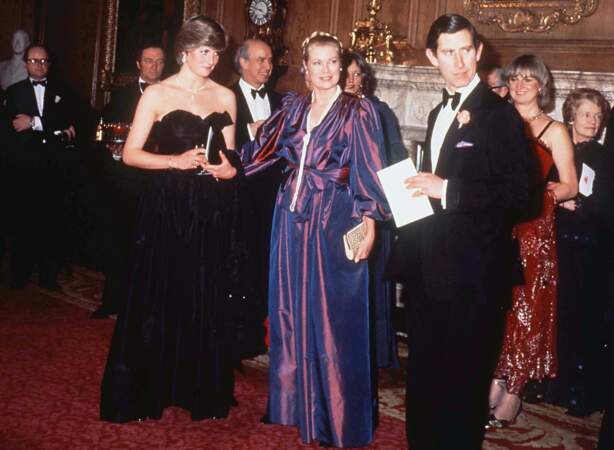 La princesse Diana dans une robe bustier noire, dessinée par David et Elizabeth Emanuel, avec Grace Kelly et le prince Charles, lors d'un gala à Londres en 1981.