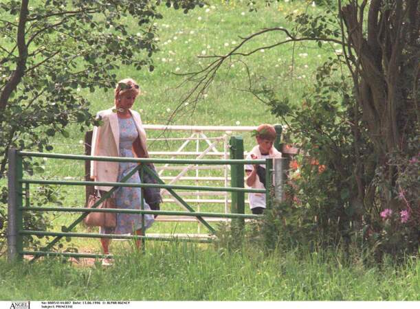 La princesse Diana dans une robe à imprimé floral bleu ciel, avec son fils le prince Harry dans les jardins de l'école Ludgrove en 1996.