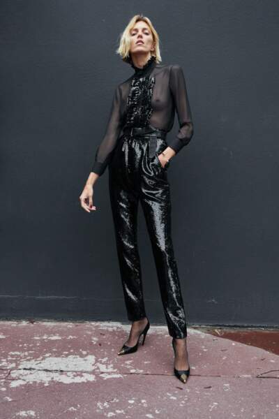 Anja Rubki sexy dans un chemisier en organza transparent au col jabot à sequins noirs assortie à son pantalon de costume taille haute pour la dernière campagne "Le Smoking" signée Saint Laurent.