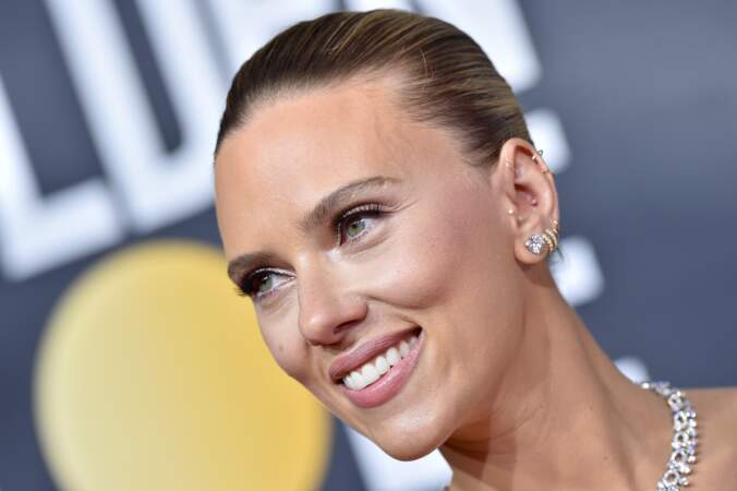 Maquillage lumineux et cheveux plaqués en arrière et noués en un petit chignon, Scarlett Johansson est sublime.