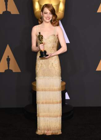 Emma Stone lors de la 89e cérémonie des Oscars à Hollywood en 2017. Pour recevoir son prix de meilleure actrice, elle porte une robe à franges dorée, signée Givenchy. Sur cette robe trônait un signe revendicateur et féministe. À vous de le trouver. 