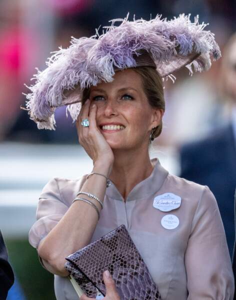 Juin 2018 : Sophie de Wessex porte une sublime tenue lors du Royal Ascot 2018 dans le Berkshire. Très moderne, elle porte une blouse transparente associée à un petit sac style peau de serpent et un chapeau à plume couleur lilas. Un look " bestial " très stylé. 