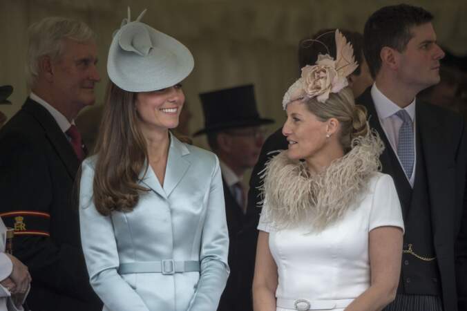 16 juin 2004 : Sophie de Wessex est en compagnie de Kate Middleton pour la cérémonie Garter en la chapelle Saint George au château de Windsor. Les deux femmes semblent proches depuis plusieurs années. Cette robe blanche au col à froufrou est une robe recyclée comme un grand nombre de ses vêtements. 