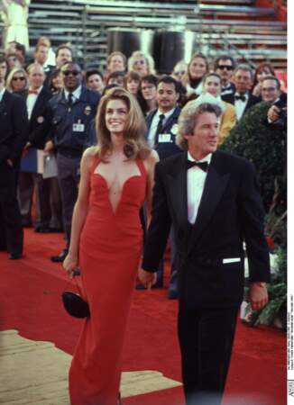 Cindy Crawford est accompagnée de Richard Gere lors de la cérémonie des Oscars en 1991. Elle porte une sublime robe rouge au décolleté plongeant et structuré de la maison Versace
