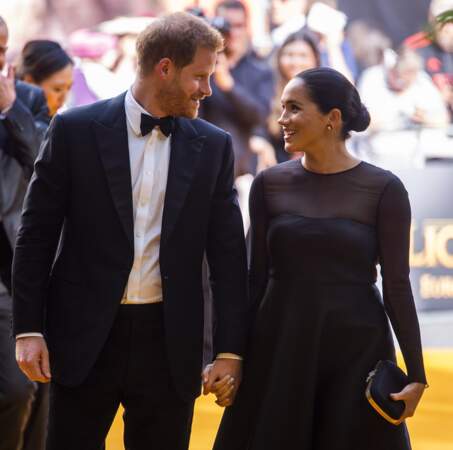 Meghan Markle porte un chignon bas avec les cheveux tirés en arrière avec une petite robe noire, laissant apparaître ses formes à la première du film "Le Roi Lion" à Londres le 14 juillet 2019