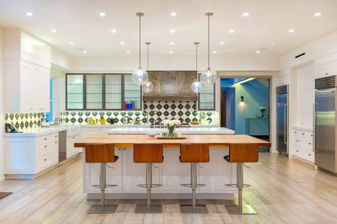 L’élégante cuisine américaine dispose de deux ilots recouverts de marbre et d’un plancher en bois