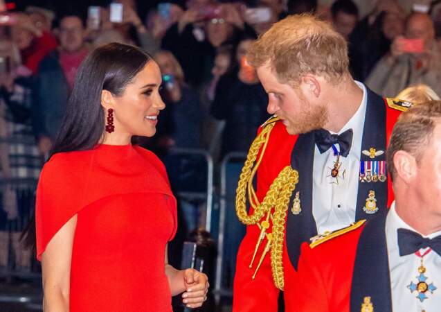 Le prince Harry admire Meghan Markle, son épouse, sublime dans sa robe-cape rouge Safiyaa et son brushing lisse parfait.