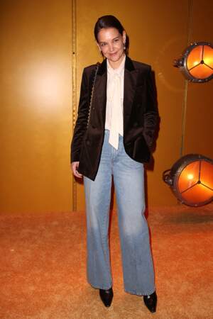 Katie Holmes twiste son jean flare avec une blouse à col lavallière et une veste en velours.