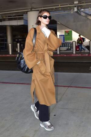 Kaia Gerber porte un manteau en cachemire camel et une paire de New Balance 574 à son arrivée à l'aéroport de LAX