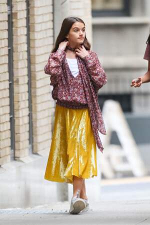 Suri Cruise  : une vraie fille en jupe plissée dorée et blouse fleurie.