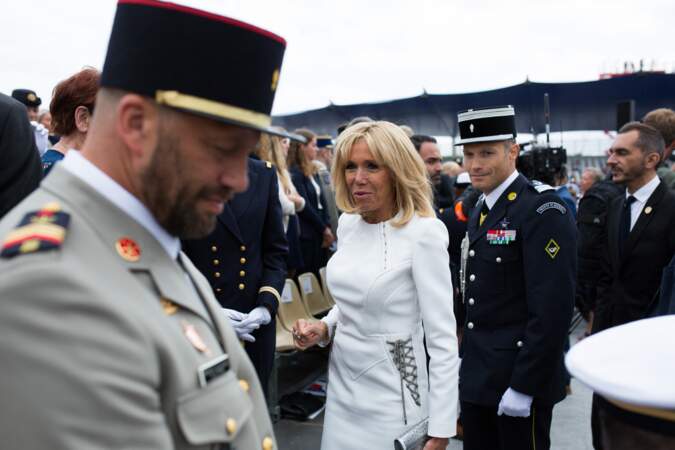 Détail remarqué sur la robe à manches longues de Brigitte Macron ce 14 juillet 2019 : ses laçages argentés au niveau de hanches, raccord avec sa pochette.