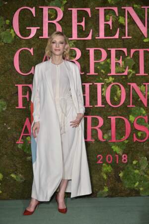 Cate Blanchett en total look blanc, revisite le costume tailleur et porte une longue veste blazer associée à une paire de talons rouges.