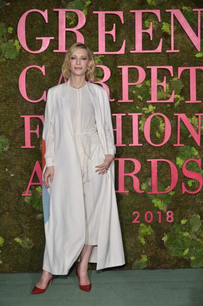 Cate Blanchett en total look blanc, revisite le costume tailleur et porte une longue veste blazer associée à une paire de talons rouges.