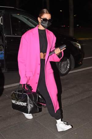 Hailey Baldwin Bieber illumine son look street avec un long manteau rose flashy.