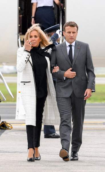 Brigitte Macron offre un look noir et blanc très sobre avec un manteau long en tweed signé Chanel.