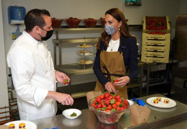 Le chef Adam Fargin guide Kate Middleton pour la préparation des desserts aux fraises dans les cuisines du All England Lawn Tennis and Croquet Club de Wimbledon à Londres, le 2 juillet 2021.