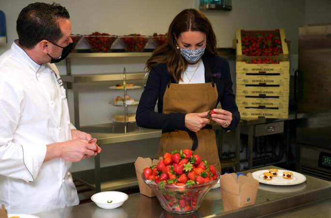Kate Middleton coupe des fraises dans les cuisines du All England Lawn Tennis and Croquet Club de Wimbledon à Londres, le 2 juillet 2021.