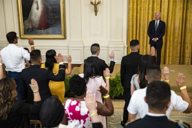 Le président américain Joe Biden se tient debout alors qu'un nouveau groupe de citoyens américains naturalisés prête le serment d'allégeance lors d'une cérémonie de naturalisation.