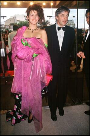 Sophie Marceau habillée d'une robe à fleurs, gantée de vert et drapée dans une étole shocking pink, au côté de son compagnon et pygmalion Andrzej Zulawski, au Festival de Cannes, en 1988.