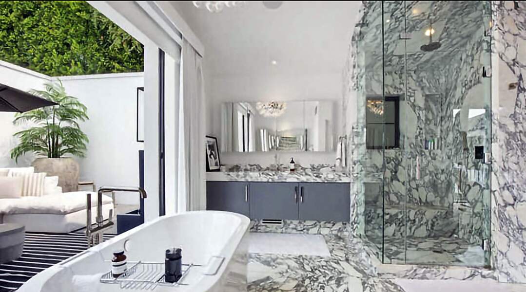 Cette salle de bain toute en marbre avec baignoire et douche à l’italienne donne un accès direct à la terrasse