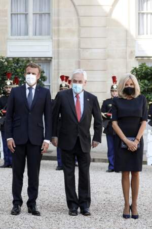 Brigitte Macron en robe droite qui arrive juste au-dessus du genou et escarpins noirs.