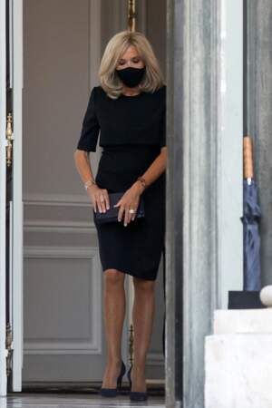Brigitte Macron très chic et sobre en robe noire, escarpins noirs et sac à main noir, jusqu'au masque assorti.