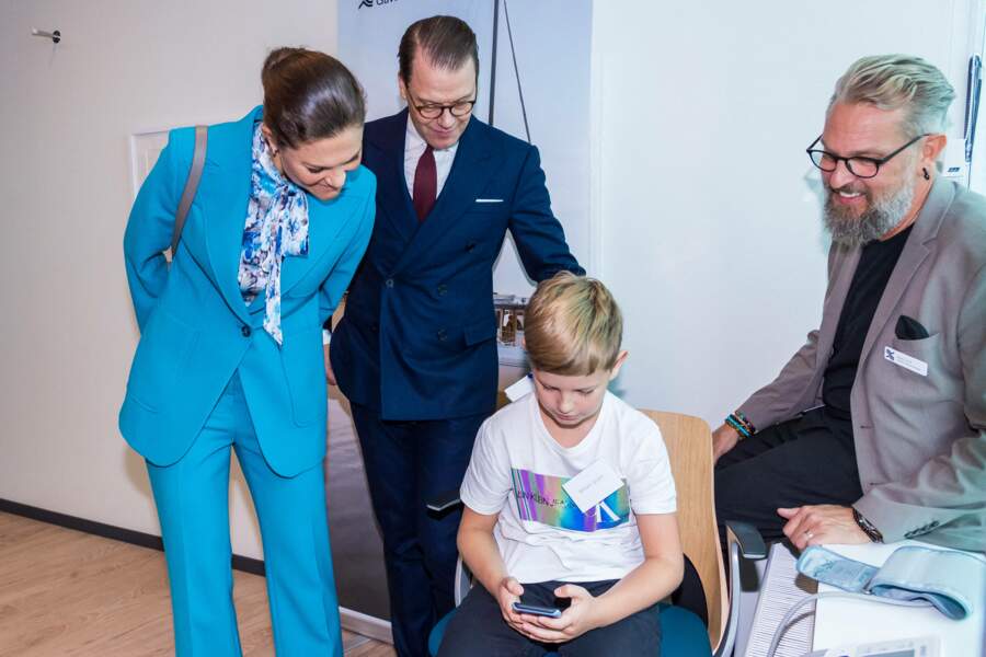 Le prince et la princesse de Suède discutent avec un enfant lors de leur visite dans un centre de santé