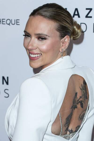 Scarlett Johansson radieuse en veste de smoking ouverte qui laisse découvrir son tatouage dans son dos, le 18 novembre 2021.