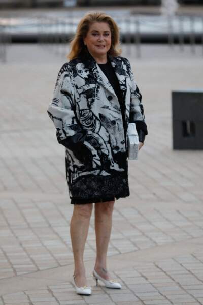 Catherine Deneuve en manteau noir et blanc lors du défilé Vuitton printemps été 2022