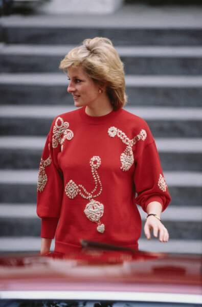 Icône mode ultime, la princesse Diana était aussi une grande amatrice des pulls à imprimés originaux. Bien que porté à l'occasion de la rentrée scolaire de ses fils William et Harry en septembre 1989, ce sweat rouge orné de clochettes dorées serait une pièce appropriée pour un look festif, à l'occasion des fêtes de Noël. 