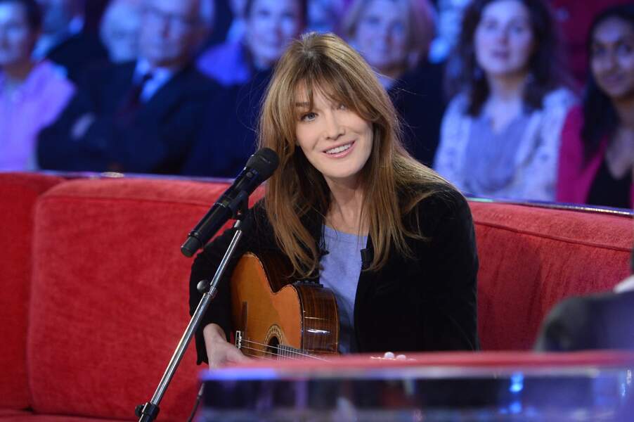 France rideau et look décontracté, Carla Bruni s'empare de sa guitare sur le canapé rouge de Michel Drucker lors de l'émission "Vivement dimanche", le 10 décembre 2014.