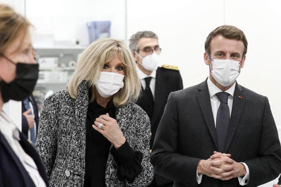 Brigitte Macron porte la veste en tweed grise sur une blouse noire et un pantalon noir.