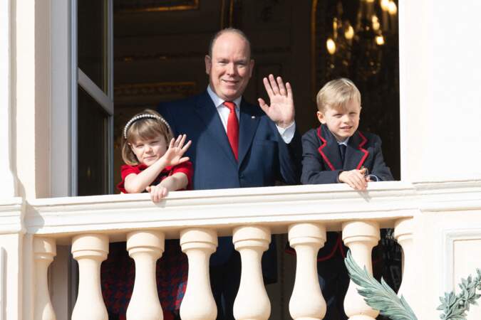 En l'absence de son épouse Charlene de Monaco, le prince Albert fait un signe de la main aux Monégasques, aux côtés de ses jumeaux Jacques et Gabriella, depuis le balcon du Palais.