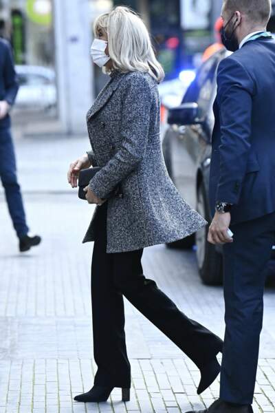 Brigitte Macron en pantalon noir, veste longue et pochette noire à Bruxelles, Belgique, le 17 février 2022