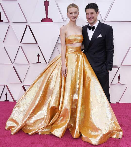 Carey Mulligan en robe longue de bal dorée signée Valentino, pose avec son mari, Marcus Mumford aux Oscars 2021