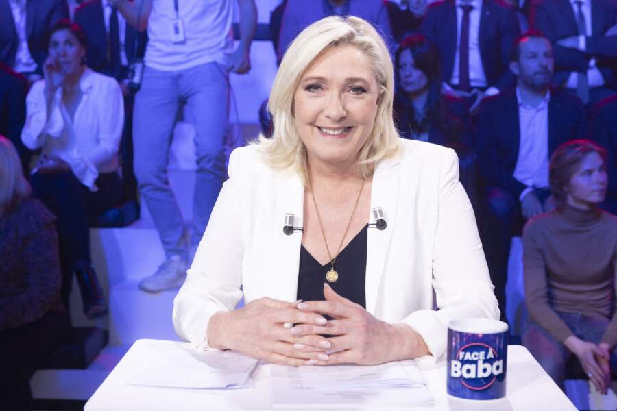 Marine Le Pen et son costume de 2022 : des couleurs claires, un médaillon qui ne la quitte jamais, un blond froid et une manucure ultra soignée, le 16/03/2022