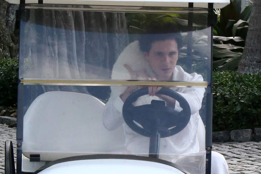 À bord d'une voiturette de golf, le futur marié portait un ensemble confortable en soie avec des claquettes/chaussettes