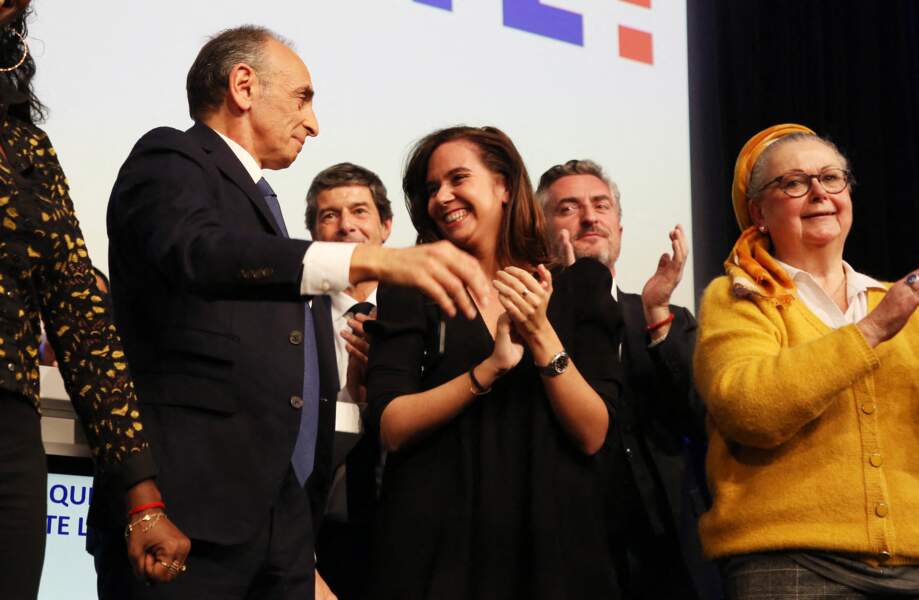 Christine Boutin, Eric Zemmour et Sarah Knafo souriants sur la scène de la Mutualité à Paris le 10 avril 2022.
