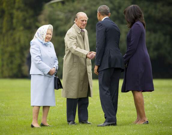 Élégante dans un ensemble bleu layette, à l'occasion de sa rencontre avec le couple présidentiel Barack et Michelle Obama le 22 avril 2016, la reine Elizabeth II a caché sa mise en pli sous un foulard pastel.