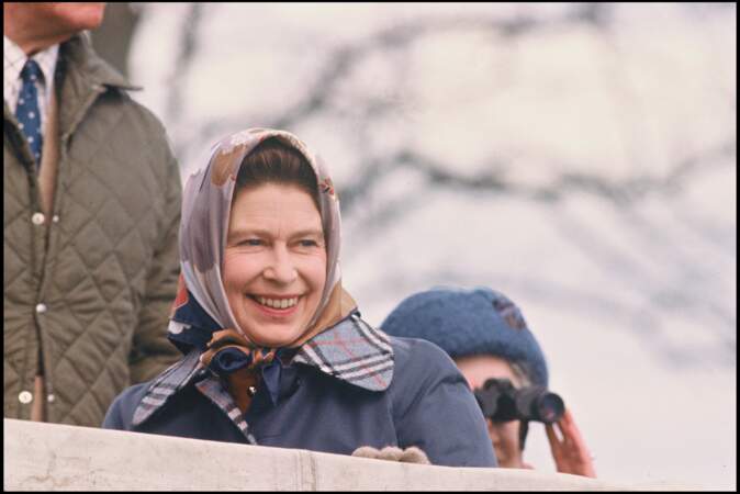 Pour se rendre à Badminton, la reine Elizabeth II a assorti son carré de soie avec sa veste matelassée bleu marine, le 23 avril 1979.